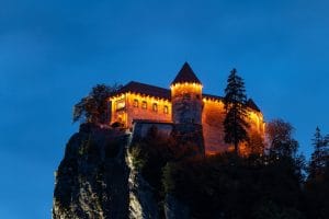Bled Castle illuminated at night on the cliff above Lake Bled