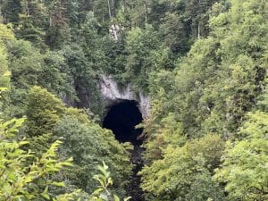 Karst cave entrance surrounded by forest in Rakov Škocjan Landscape Park