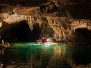 Explorer beside the emerald water of the 13th Lake in Križna Jama Cave