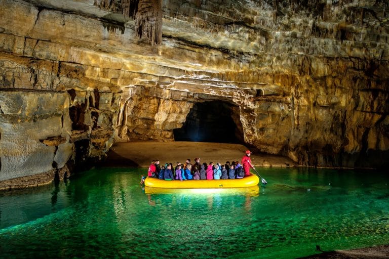 Visitors exploring the First Lake inside Križna Jama Cave by inflatable boat