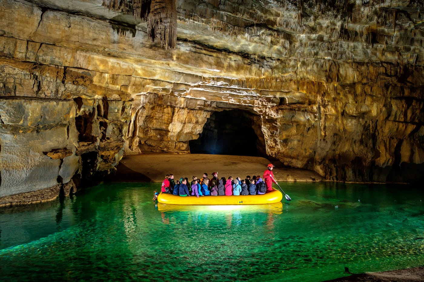 Visitors exploring the First Lake inside Križna Jama Cave by inflatable boat