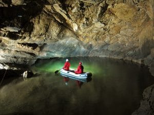Two visitors crossing the Second Lake by inflatable boat in Križna Jama Cave