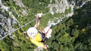 Zipline rider crossing high above the forested Učja Canyon near Bovec.