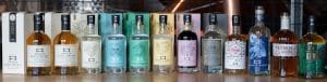 A row of Broken Bones whisky, gin, vodka, brandy and rum bottles displayed on a wooden counter.