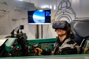 Visitor wearing a virtual reality headset while seated at the controls of the flight simulator in Pivka.