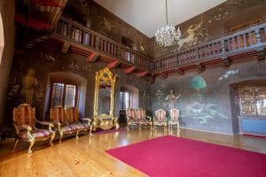 Dark painted walls, a wooden upper gallery and ornate seating inside the hall at Prem Castle.