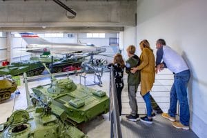 Family overlooking a hall filled with tanks, armoured vehicles and historic aircraft at the Pivka museum.