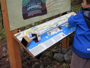Child using an outdoor Roman road activity board on the Ad Pirum archaeological trail.