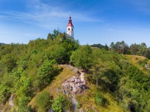 Two adults and two children stand on a hillside viewing platform below the Church of St. Ivan bell tower.