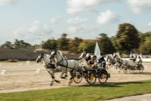 Horse-drawn carriages move through an outdoor arena during an event.